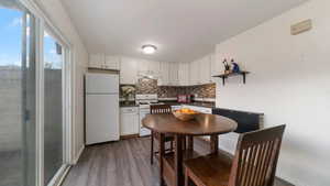 Kitchen with white appliances, white cabinets, sink, hardwood / wood-style flooring, and decorative backsplash