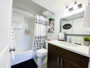 Downstairs Full bathroom featuring tile patterned floors, shower / bath combo with shower curtain, vanity, and toilet