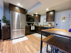 Downstairs Kitchen featuring sink, dark brown cabinets, light wood-type flooring, and black/Stainless appliances