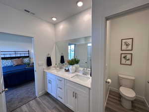 Bathroom with hardwood / wood-style floors, vanity, and toilet