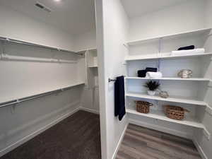 Spacious closet with dark hardwood / wood-style flooring