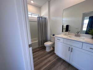 Full bathroom with shower / bath combination with curtain, vanity, toilet, and wood-type flooring