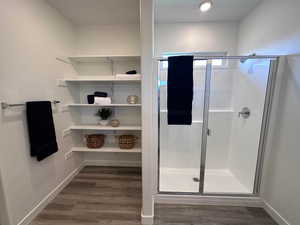 Bathroom featuring hardwood / wood-style floors and a shower with door