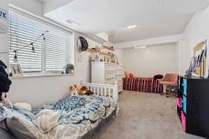 Bedroom with light colored carpet and a textured ceiling