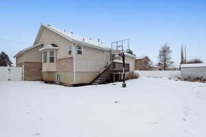 Snow covered back of property featuring basketball court