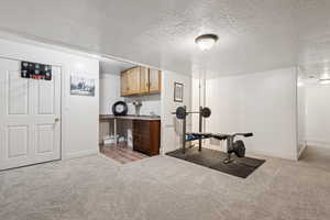 Exercise area with a textured ceiling and light carpet