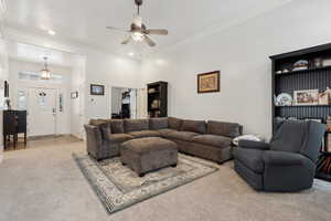 Living room featuring ceiling fan, a towering ceiling, carpet floors, and ornamental molding