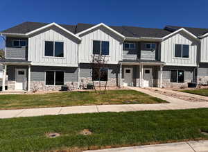 View of front facade featuring cooling unit and a front yard