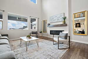 Living room with dark hardwood / wood-style flooring and a high ceiling