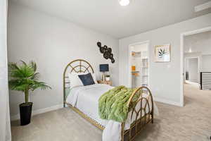 Bedroom with a walk in closet, light carpet, and a closet