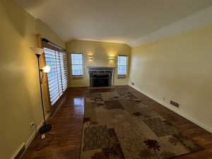 Unfurnished living room with vaulted ceiling and dark wood-type flooring