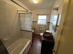 Full bathroom with hardwood / wood-style floors, a textured ceiling, toilet, vanity, and tile walls