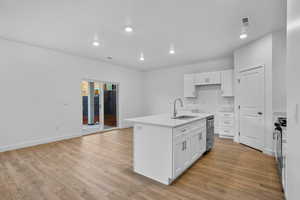 Kitchen with a center island with sink, white cabinetry, stainless steel appliances, and sink