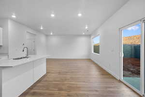 Kitchen featuring a healthy amount of sunlight, light wood-type flooring, white cabinetry, and sink