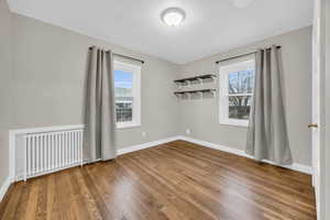 Spare room featuring radiator heating unit, a healthy amount of sunlight, and hardwood / wood-style flooring