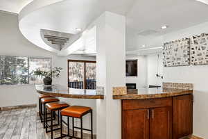 Kitchen featuring recessed lighting, light wood-type flooring, a kitchen bar, and a healthy amount of sunlight