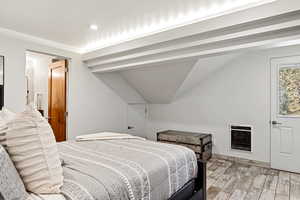 Bedroom featuring heating unit, light wood-style flooring, vaulted ceiling, and recessed lighting