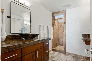 Bathroom with a walk in shower, wood finished floors, vanity, and visible vents