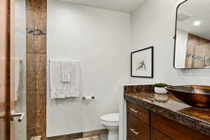 Full bathroom with toilet, recessed lighting, vanity, visible vents, and tiled shower