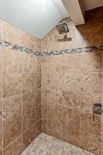 Bathroom featuring lofted ceiling and tiled shower