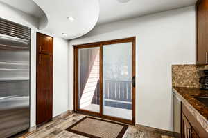 Kitchen featuring baseboards, wood finished floors, stainless steel built in refrigerator, backsplash, and recessed lighting