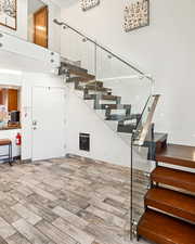 Stairs with a towering ceiling, heating unit, and wood tiled floor