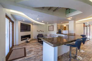 Kitchen featuring a kitchen breakfast bar, kitchen peninsula, and dark stone counters