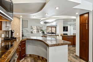 Kitchen with black electric stovetop, recessed lighting, wood finished floors, built in microwave, and a peninsula