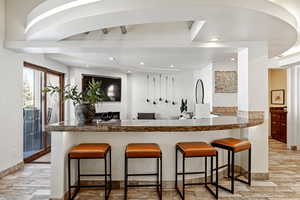 Kitchen with dark countertops, light wood finished floors, a peninsula, and a kitchen breakfast bar