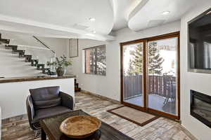 Living area featuring light wood-style flooring, recessed lighting, visible vents, baseboards, and stairs