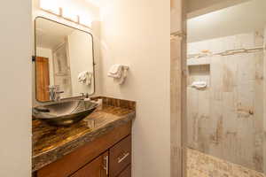 Bathroom featuring tiled shower and vanity