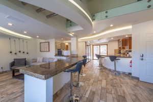 Kitchen with a kitchen breakfast bar, light wood-type flooring, and dark stone counters