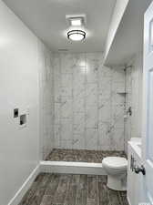 Bathroom featuring tiled shower, vanity, and toilet