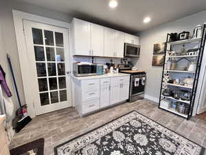 Kitchen with white cabinetry, backsplash, and appliances with stainless steel finishes