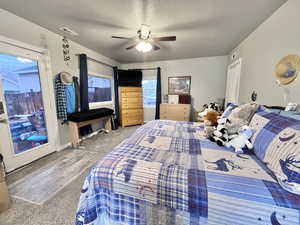 Carpeted bedroom featuring ceiling fan and a textured ceiling