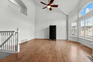 Unfurnished living room featuring ceiling fan, high vaulted ceiling, and light wood-type flooring