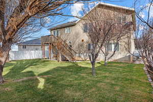 Rear view of property with a lawn and a deck