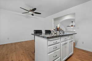 Kitchen featuring white cabinets, light hardwood / wood-style floors, and dark stone counters