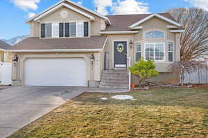 View of front of house featuring a mountain view, a garage, and a front lawn