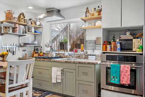 Kitchen featuring stainless steel oven, sink, and island exhaust hood