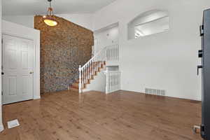 Entrance foyer featuring wood-type flooring and high vaulted ceiling