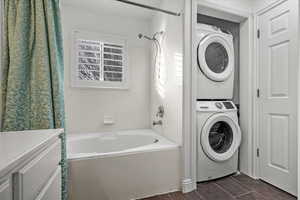 Washroom featuring stacked washing maching and dryer and plenty of natural light