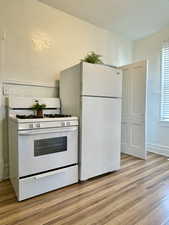 Unit #1 - Kitchen with light wood-type flooring and white appliances