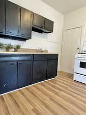 Unit #1 - Kitchen featuring electric stove, sink, and light hardwood / wood-style floors