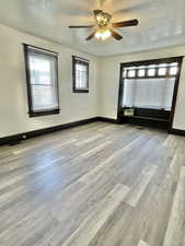 Unit #1 - Unfurnished room with ceiling fan, light wood-type flooring, and a textured ceiling