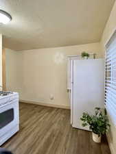 Unit #2 - Kitchen with a textured ceiling, hardwood / wood-style floors, and white appliances