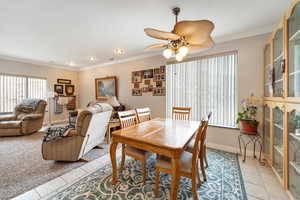 Tiled dining area with ceiling fan and crown molding
