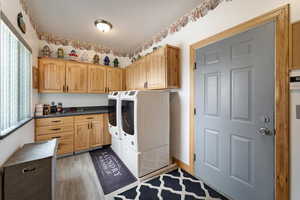 Washroom featuring washing machine and clothes dryer, a wealth of natural light, cabinets, and dark hardwood / wood-style floors