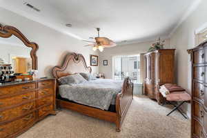 Bedroom with ceiling fan, light colored carpet, and crown molding