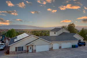 View of front of home with a mountain view, solar panels, a playground, and a garage